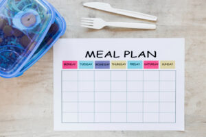 Image having a weekly meal plan with meal boxes representing importance of menu planning in meal prep business