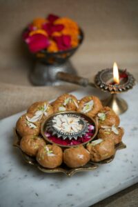 Traditional Indian sweets with almonds and diya for festive tiffin service menu